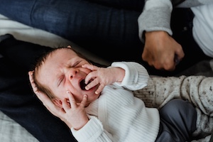 Image of infant holding an adults finger